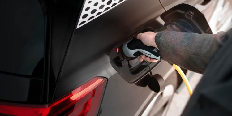 Man holding electric vehicle charging plug in car