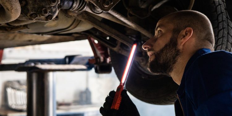 Mechanic inspecting underside of car