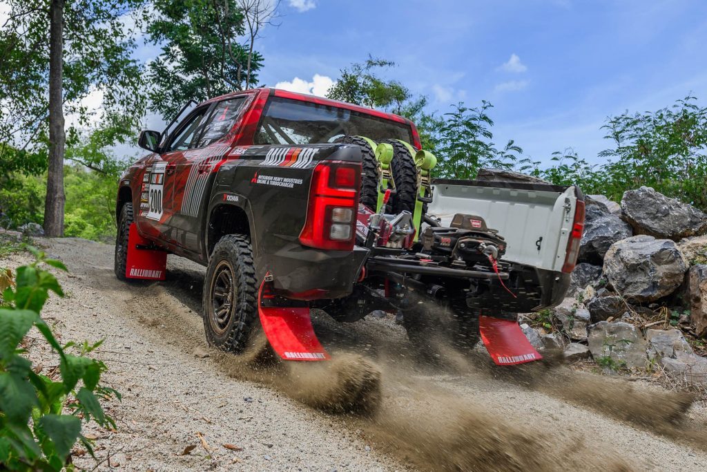 Mitsubishi Triton rally car launching on gravel road