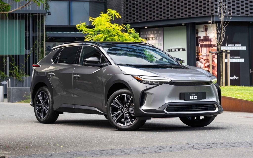 Toyota bZ4X parked in front of tree and building