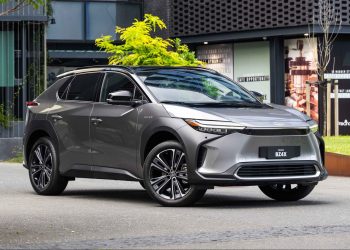 Toyota bZ4X parked in front of tree and building