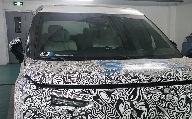 Camouflaged Volvo electric people mover parked in car park