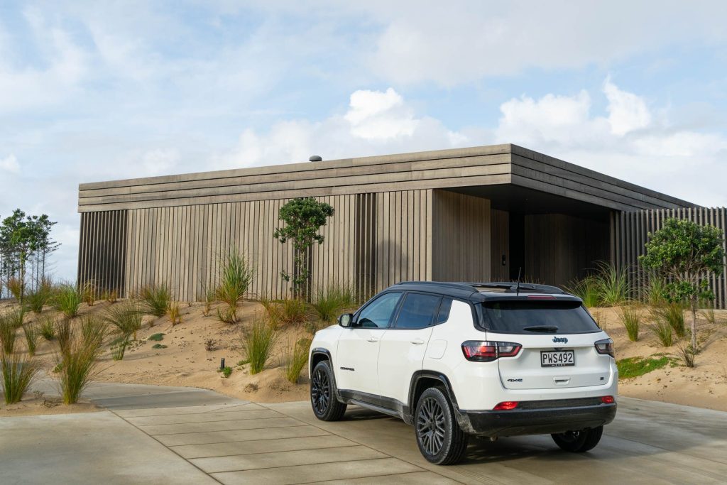 Jeep Compass S 4xe rear view parked at a bach