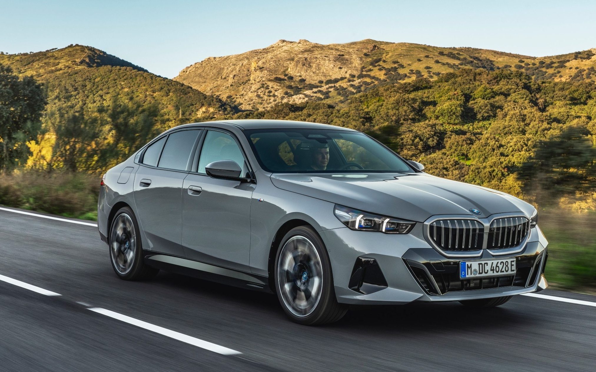 BMW 5 Series driving past mountains