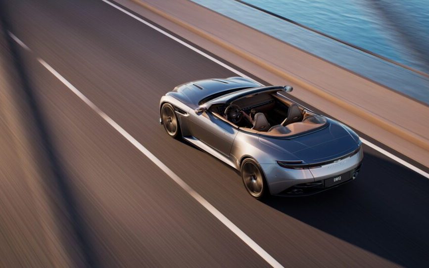 Aston Martin DB12 Volante with roof down driving on bridge
