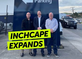 People standing by car dealership sign