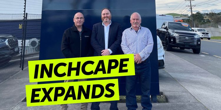 People standing by car dealership sign