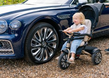 Child sitting on Bentley Mulliner tricycle next to Flying Spur