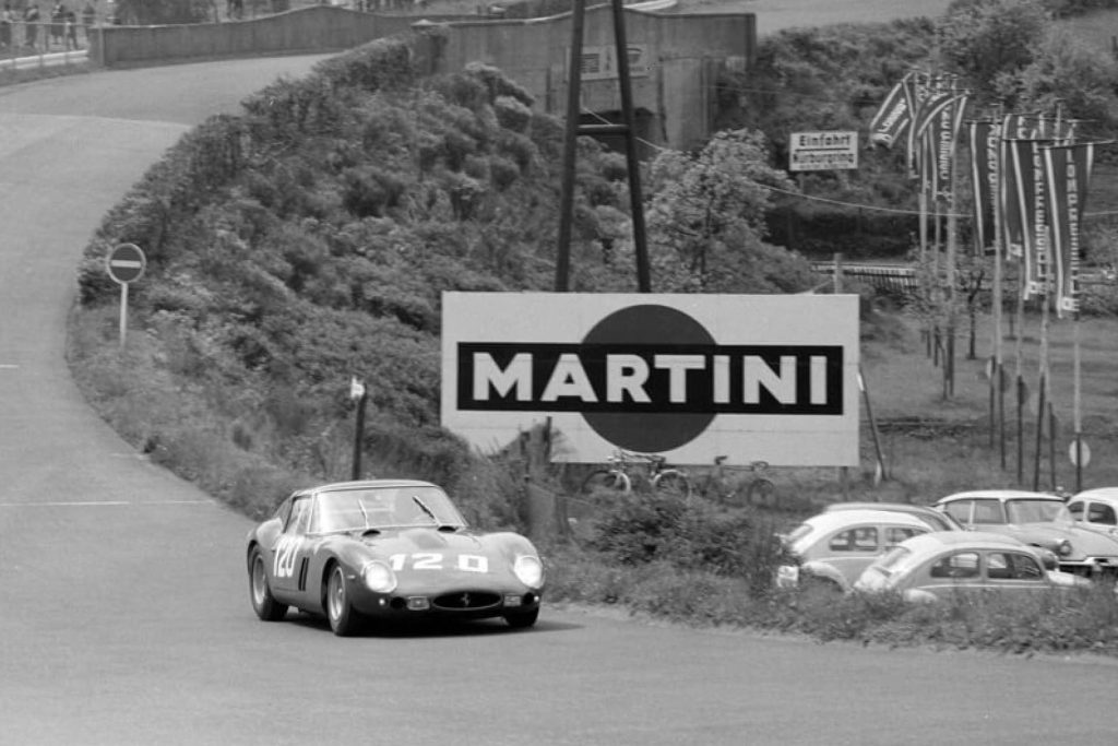 Ferrari 250 GTO racing past Martini billboard