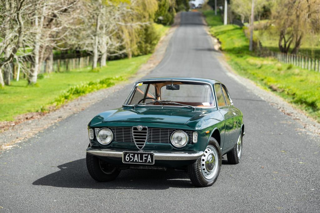 Alfa Romeo Giulia GT Sprint, painted green, parked in the middle of a quiet road