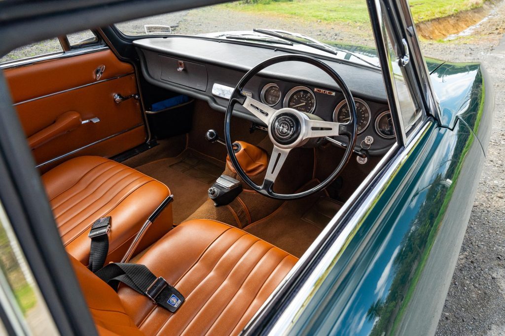 Alfa Romeo Giulia Sprint GT interior, showing steering wheel and seatbelts