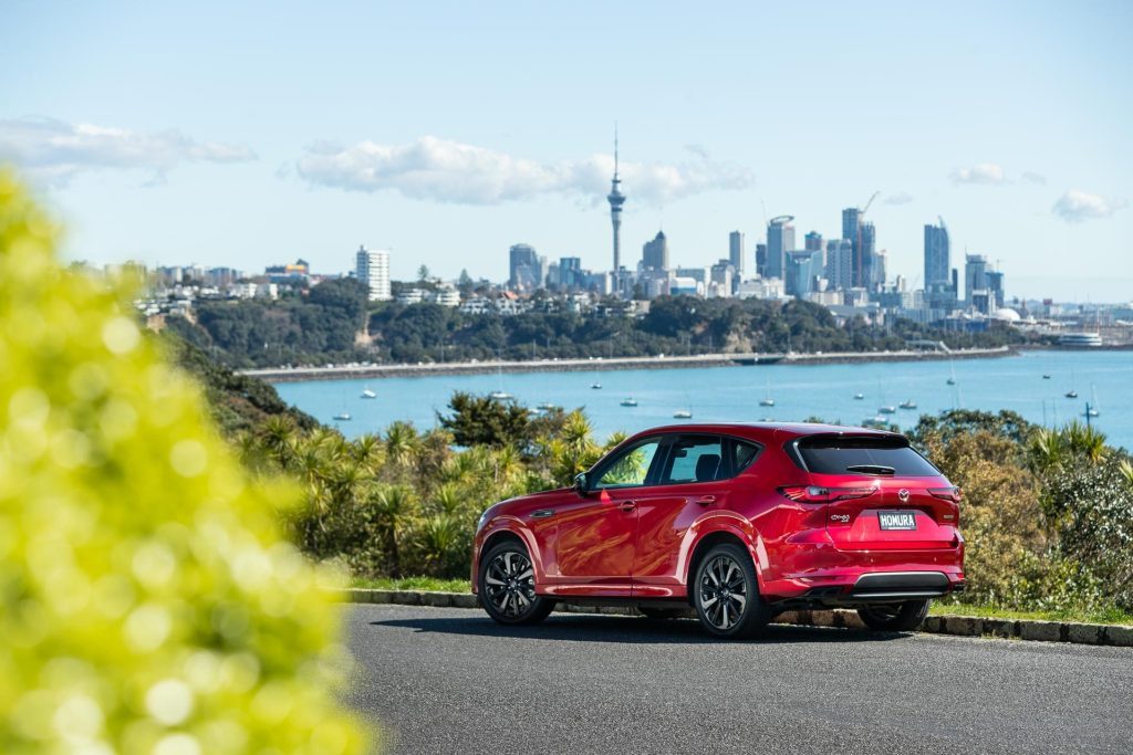 Mazda CX-60 Homura PHEV rear view, showing Auckland city behind