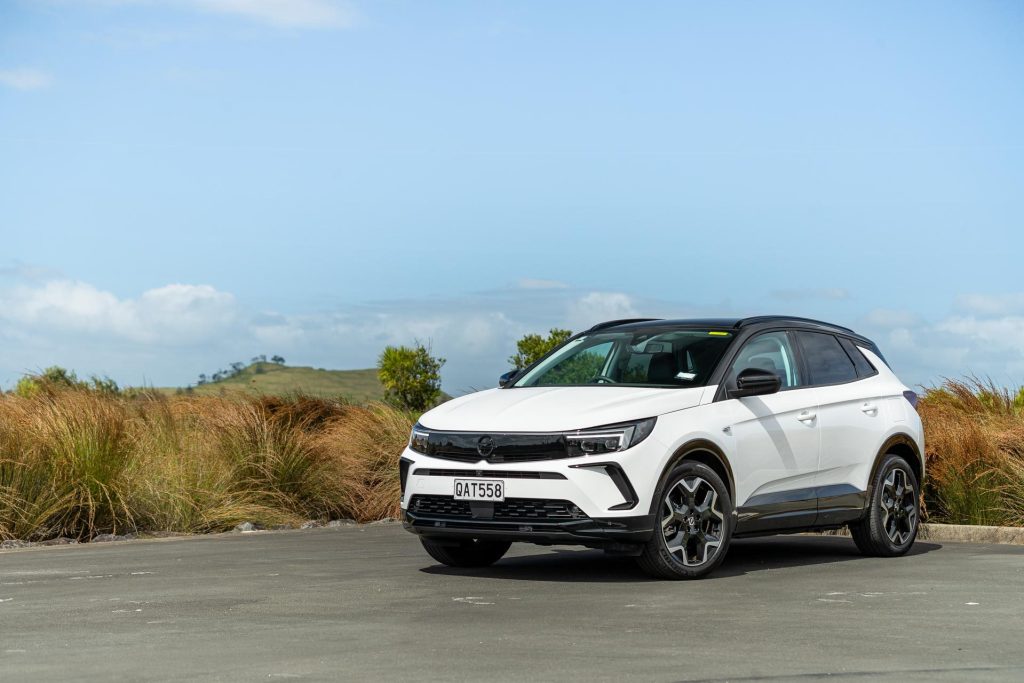 Opel Grandland PHEV in white, parked next to bushes