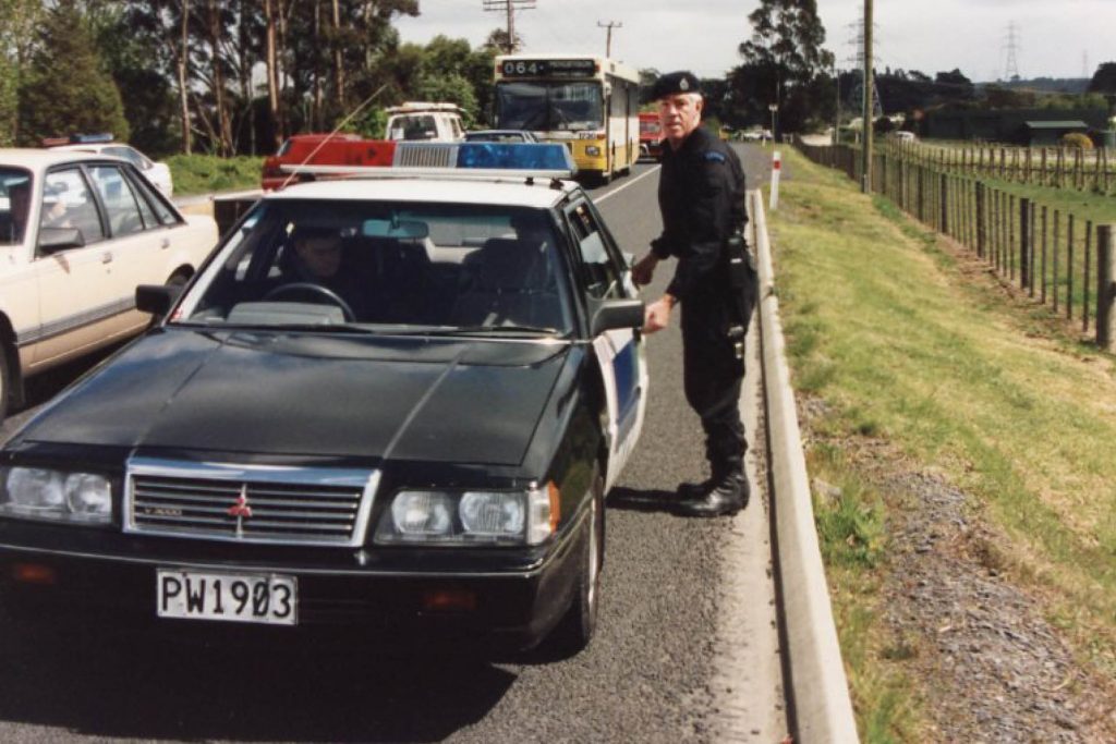 Police Officer stepping into New Zealand Police Mitsubishi V3000 GLX on side of road