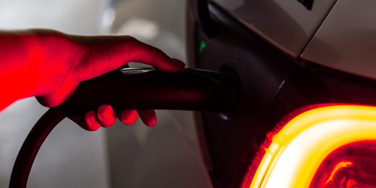 Person's hand on Tesla EV charging plug