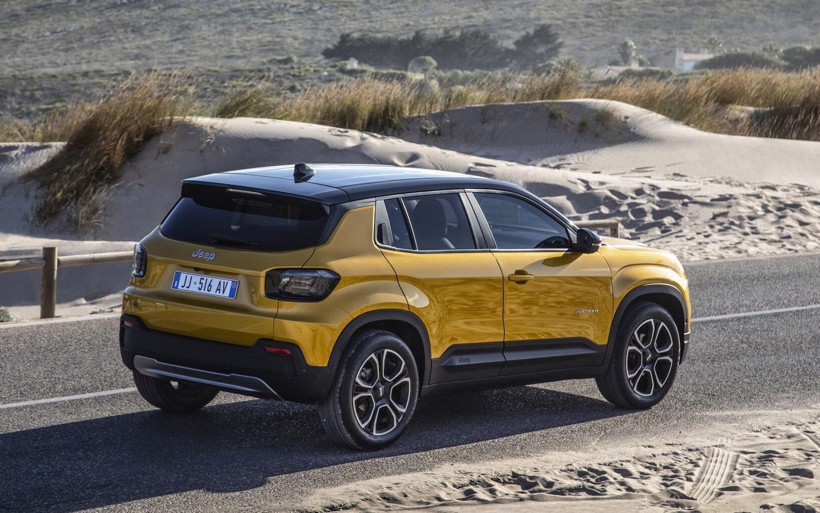 Jeep Avenger driving on road through sand dunes