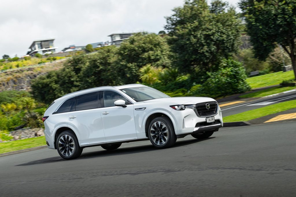 Mazda CX-90 Takami taking a corner, in a suburban area