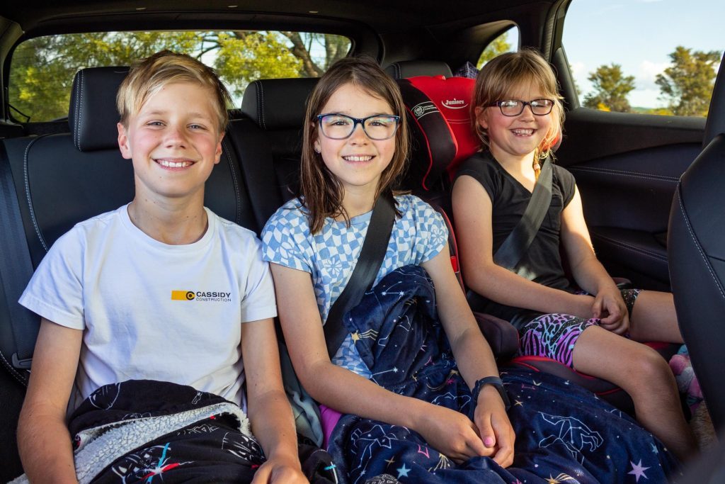 Three happy smiling kids sitting in the Nissan Qashqai Ti-L e-Power rear seats