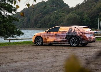 Volkswagen ID.7 Tourer parked by lake in camouflage