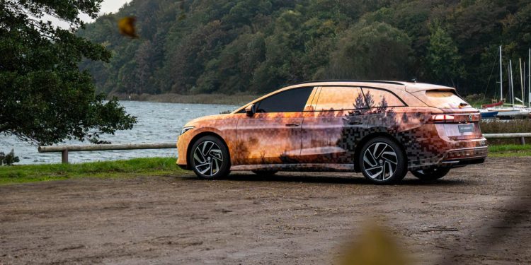 Volkswagen ID.7 Tourer parked by lake in camouflage