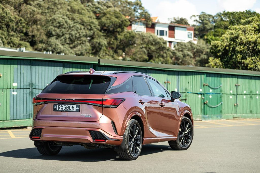 Lexus RX 500h rear quarter view in front of green background