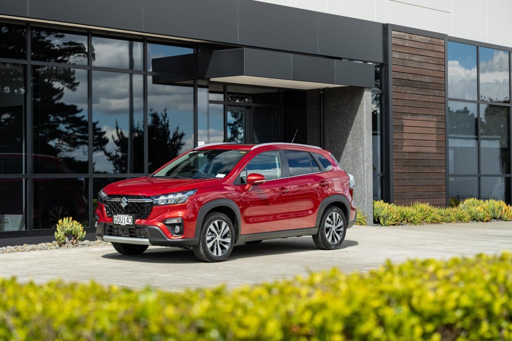 Suzuki S-Cross Hybrid in red, parked in front of an office space