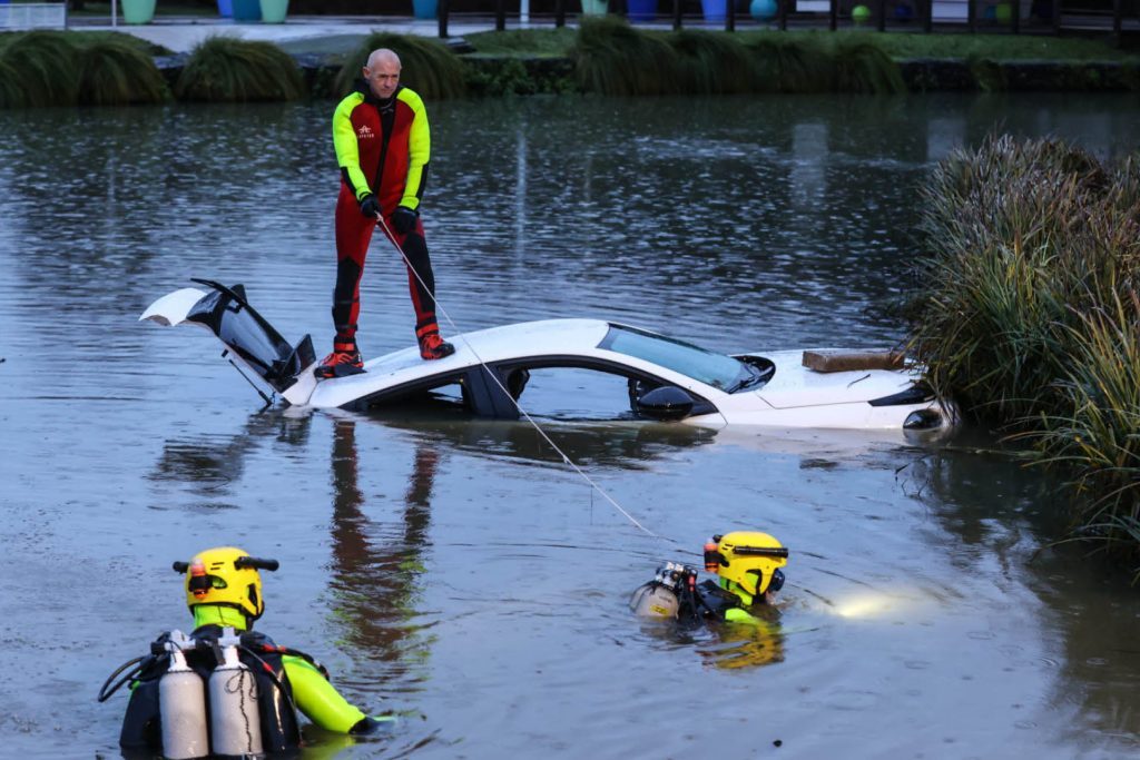 Firemen standing on Lancia Ypsilon in canal