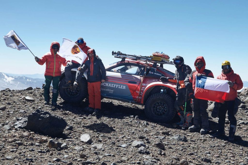 Team of people celebrate driving Porsche 911 up the world's tallest volcano