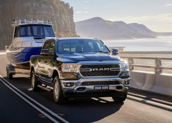 RAM 1500 Big Horn towing boat on road by sea