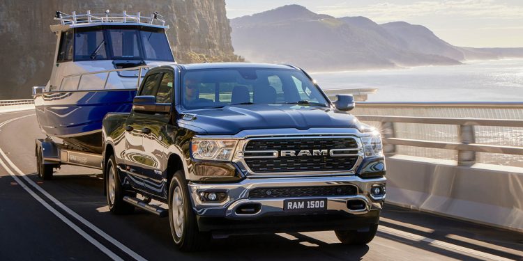 RAM 1500 Big Horn towing boat on road by sea