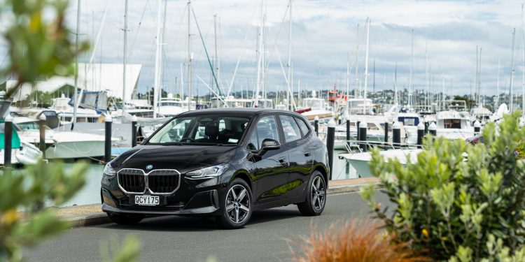 Black BMW 225e parked showing front quarter angle in a marina