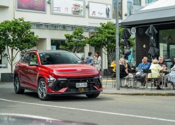 Hyundai Kona 1.6 T N Line in red driving outside a cafe