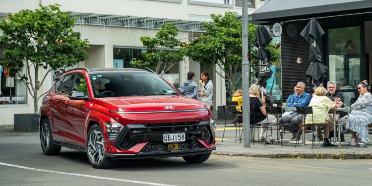 Hyundai Kona 1.6 T N Line in red driving outside a cafe