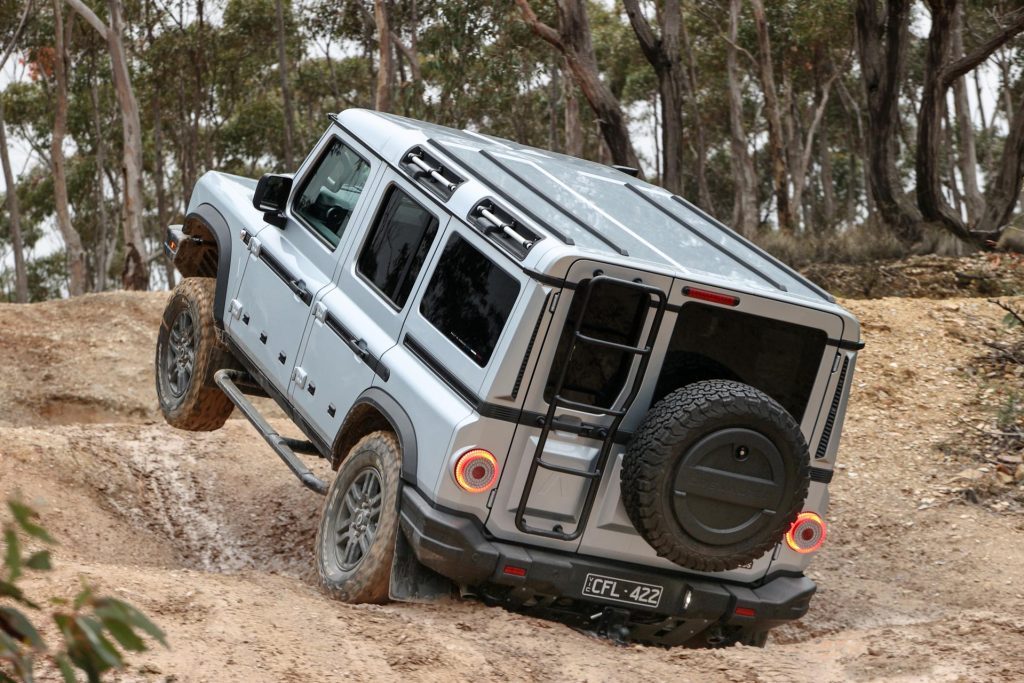 Ineos Grenadier showing its suspension travel, with front axle suspended in mid air