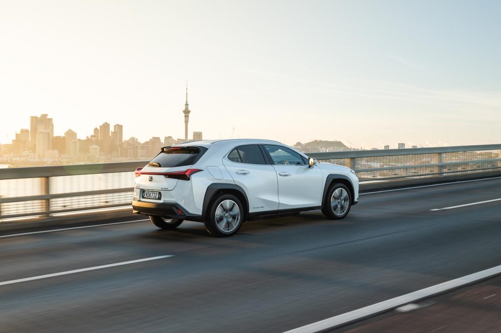 Rolling shot of Lexus UX 300e in front of Auckland's cityscape