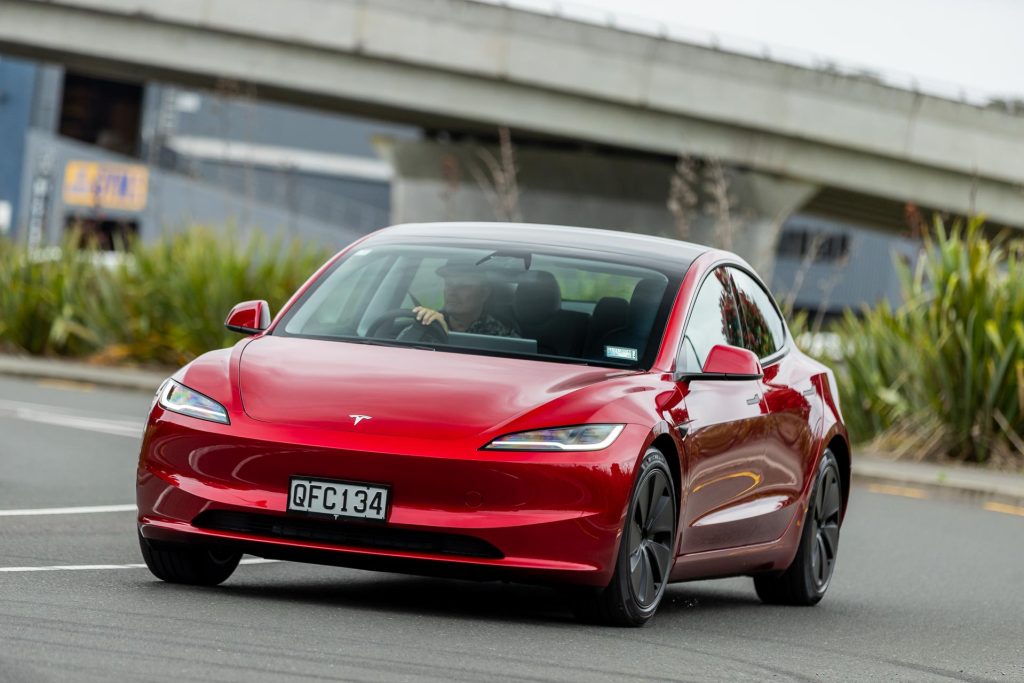 Tesla Model 3 RWD facelift in red, taking a corner