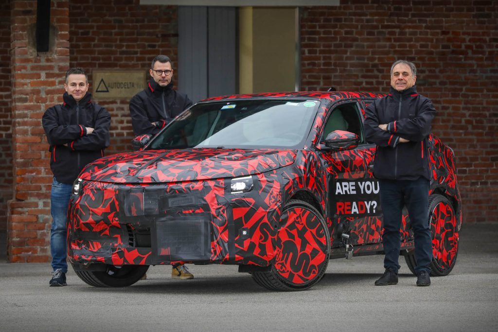Men standing around camouflaged Alfa Romeo Milano