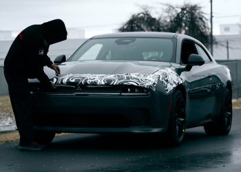 Man removing camouflage from pre-production 2024 Dodge Charger EV