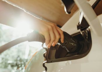 Person plugging in charging cable to EV