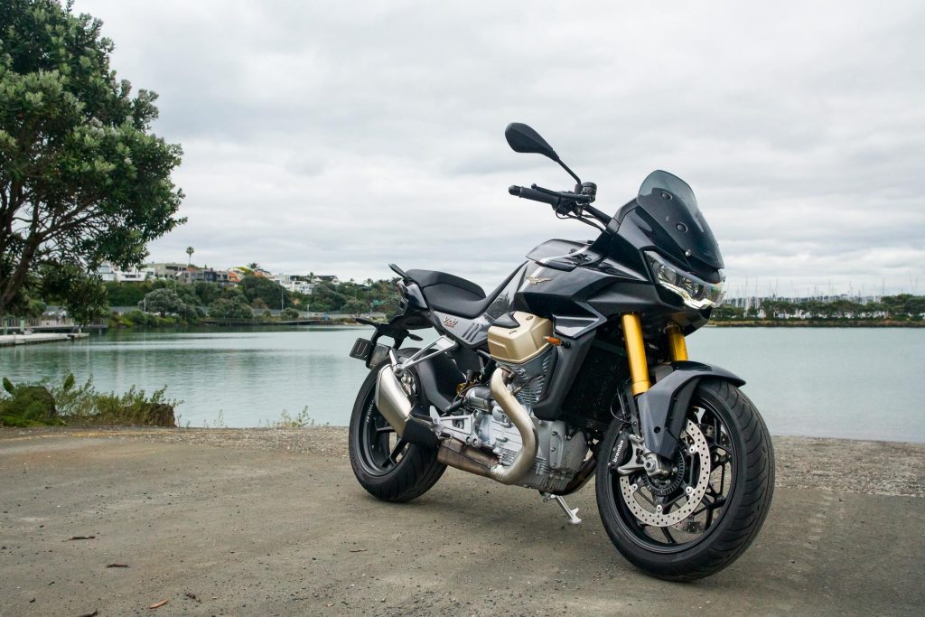 Moto Guzzi V100 Mandello in black, front quarter shot next to water