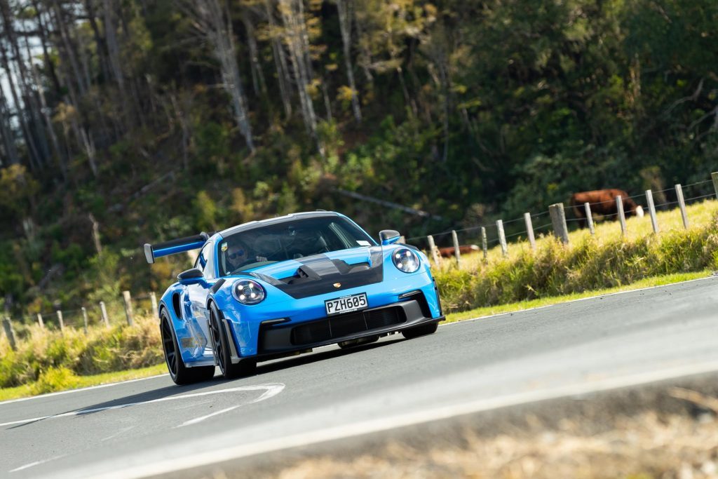 Porsche 911 GT3 RS 992 front view, cornering on a scenic road