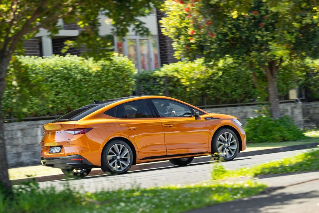 Skoda Enyaq 80 Coupe rear side view, in orange, dynamic moving shot