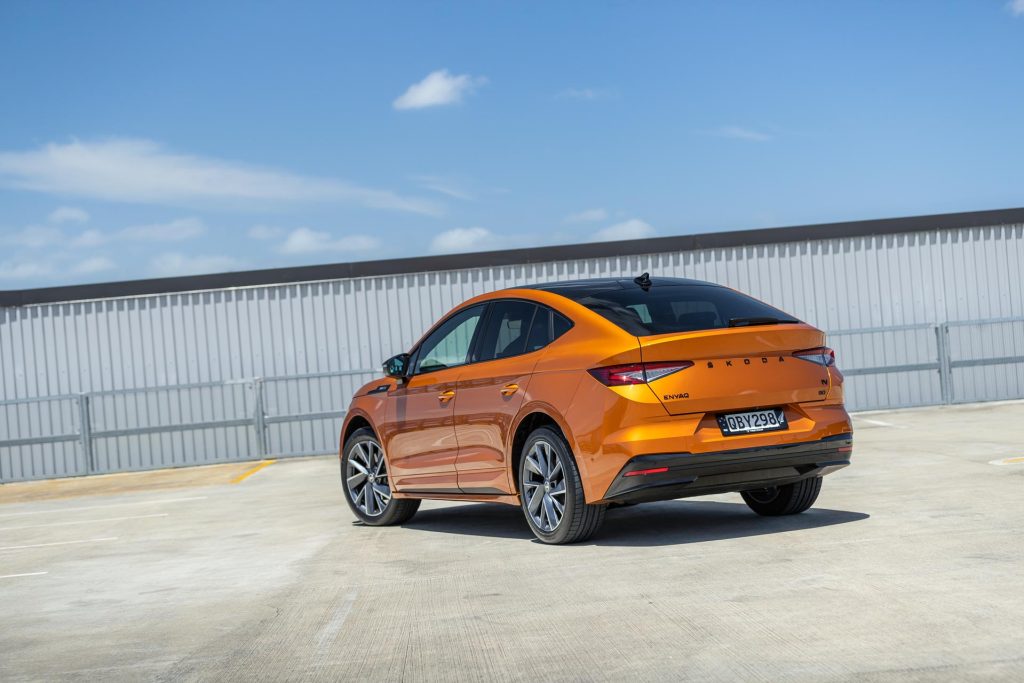 Rear quarter shot of the Skoda Enyaq 80 Coupe in orange, parked on the roof of a carpark