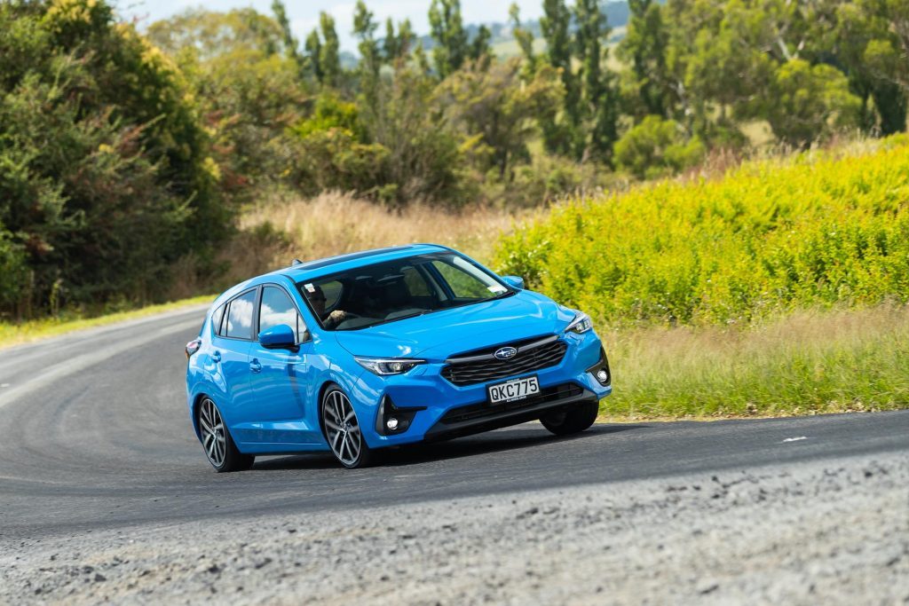 Subaru Impreza 2024 in bright blue taking a corner at pace