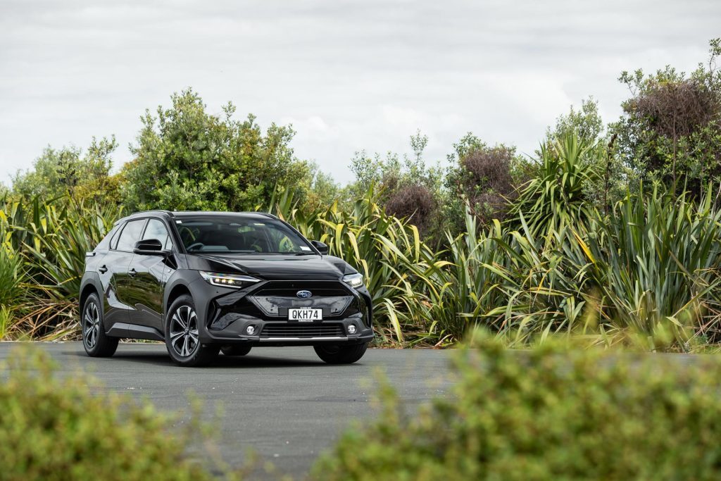 New Subaru Solterra in black, parked amongst flax bushes