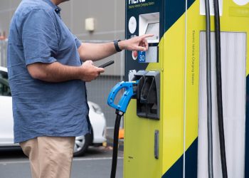 Man holding phone while using EV charger