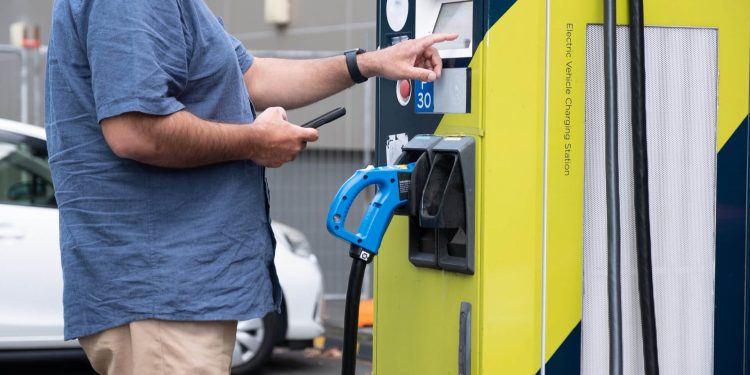 Man holding phone while using EV charger