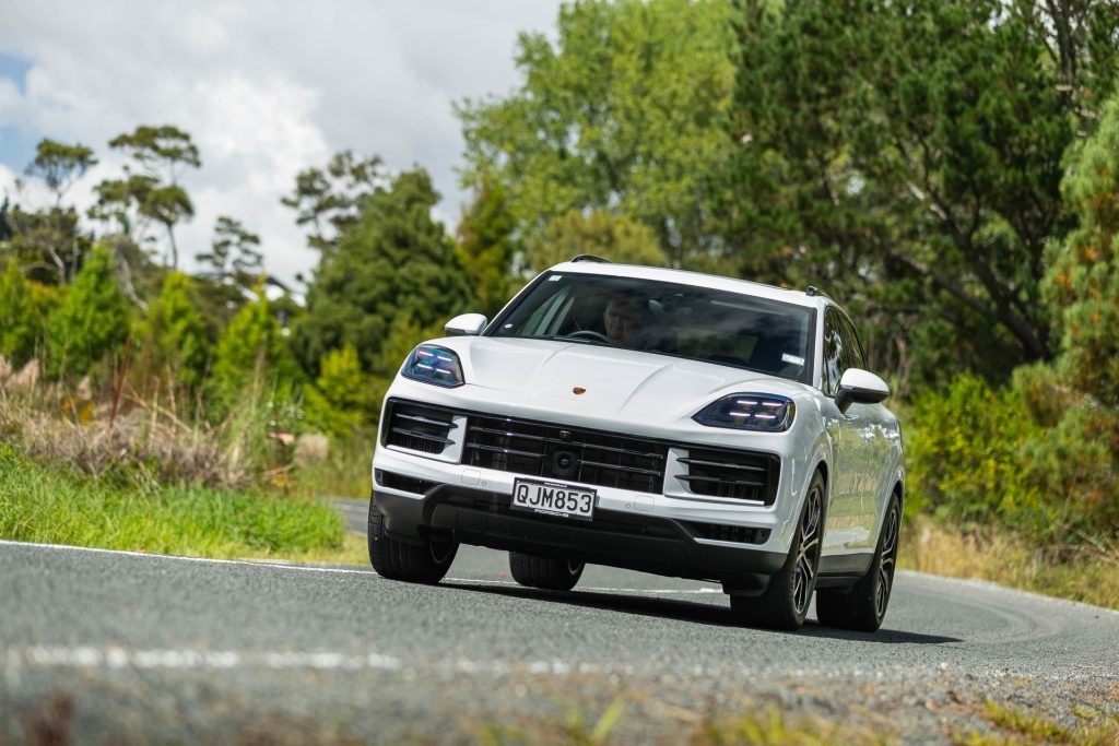 Porsche Cayenne e-Hybrid in white, taking a bend at pace