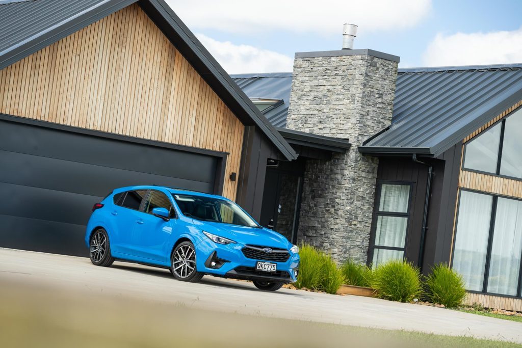 Blue 2024 Subaru Impreza, parked in front of show home