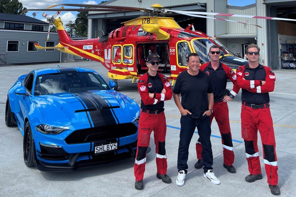 Auckland Rescue Helicopter Trust workers standing next to Ford Shelby Super Snake Wide Body Mustang prize